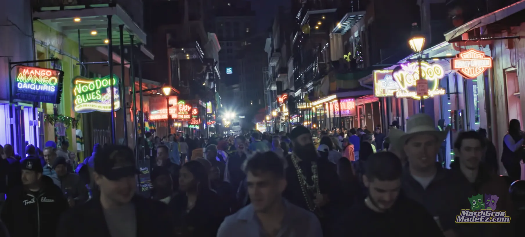 A crowd filling a neon-lit New Orleans street at night