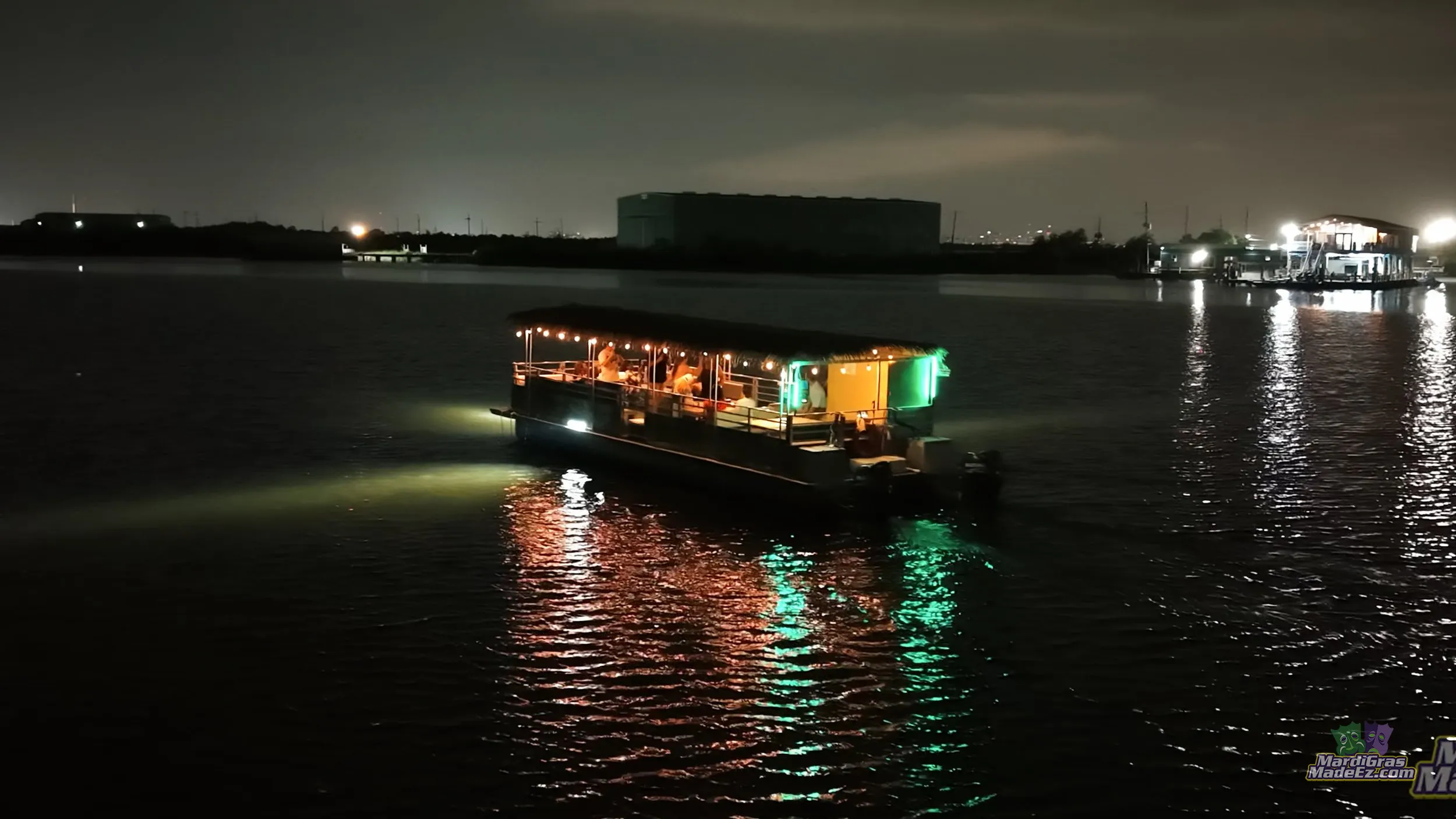A lit tour boat gliding across dark water at night